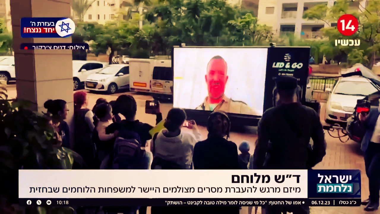 קהל צופה במסך LED שמקרין מסר מלוחם בחזית